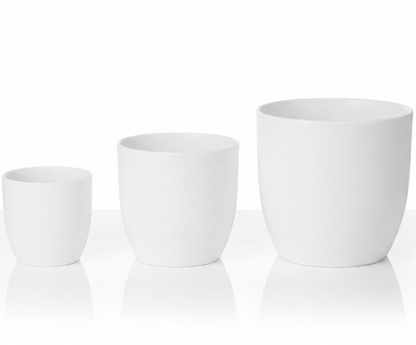 Three matte white ceramic planters in graduated sizes, arranged from smallest to largest on a reflective white surface against a white background.